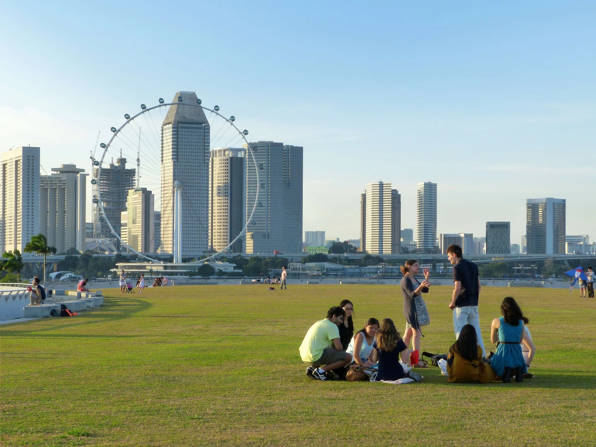 People sitting and talking on an open lawn with the city skyline behind them